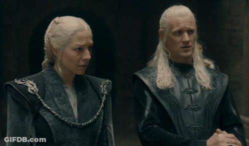 A Man And A Woman Are Standing Next To Each Other In A Dark Room GIF