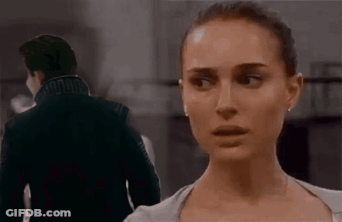 A Man And A Woman Are Standing Next To Each Other In A Dark Room . GIF