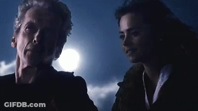 A Man And A Woman Are Standing Next To Each Other In A Dark Room With A Full Moon In The Background . GIF