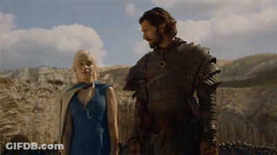 A Man And A Woman Are Standing Next To Each Other In A Field And Holding Hands . GIF