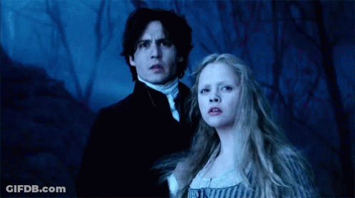 A Man And A Woman Are Standing Next To Each Other In A Forest . GIF