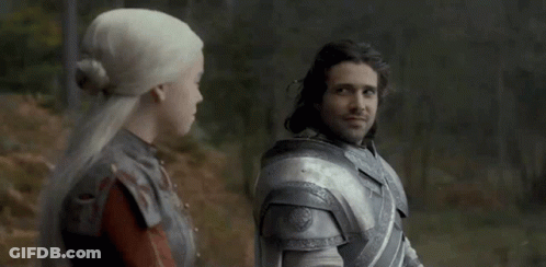 A Man And A Woman Are Standing Next To Each Other In A Forest . GIF