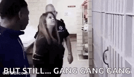 A Man And A Woman Are Standing Next To Each Other In A Jail Cell And Talking To Each Other . GIF