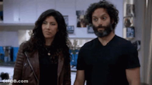 A Man And A Woman Are Standing Next To Each Other In A Kitchen . The Woman Is Wearing A Leather Jacket . GIF