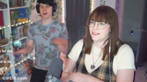 A Man And A Woman Are Standing Next To Each Other In A Living Room . GIF