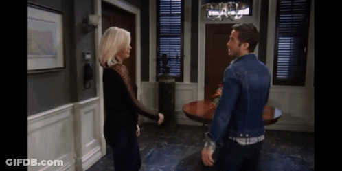 A Man And A Woman Are Standing Next To Each Other In A Living Room GIF