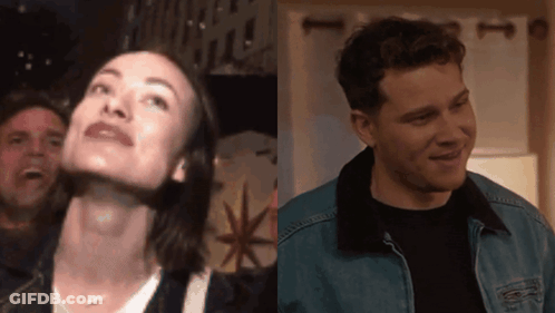 A Man And A Woman Are Standing Next To Each Other In A Room GIF