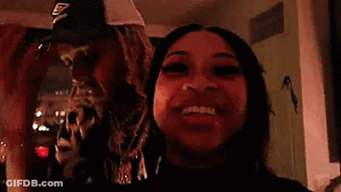 A Man And A Woman Are Standing Next To Each Other In A Room And Smiling . GIF