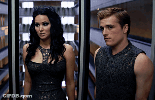 A Man And A Woman Are Standing Next To Each Other In A Room GIF