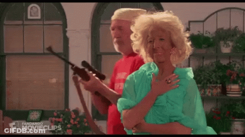 A Man And A Woman Are Standing Next To Each Other In A Room Holding A Gun . GIF