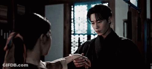 A Man And A Woman Are Standing Next To Each Other In A Room . GIF