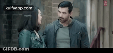 A Man And A Woman Are Standing Next To Each Other In A Room . GIF