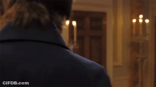 A Man And A Woman Are Standing Next To Each Other In A Room . The Woman Is Wearing A White Dress . GIF