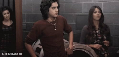 A Man And A Woman Are Standing Next To Each Other In A Room With A Brick Wall . GIF