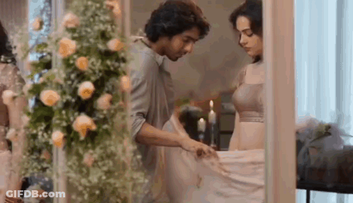 A Man And A Woman Are Standing Next To Each Other In A Room With Flowers And Candles . GIF