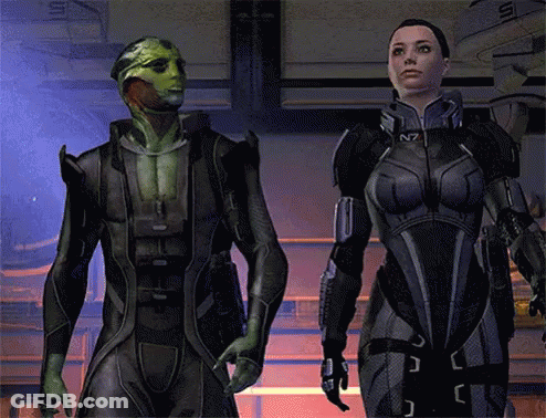A Man And A Woman Are Standing Next To Each Other In A Video Game With The Letters N7 On Their Suits GIF