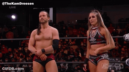 A Man And A Woman Are Standing Next To Each Other In A Wrestling Ring In Front Of A Crowd . GIF