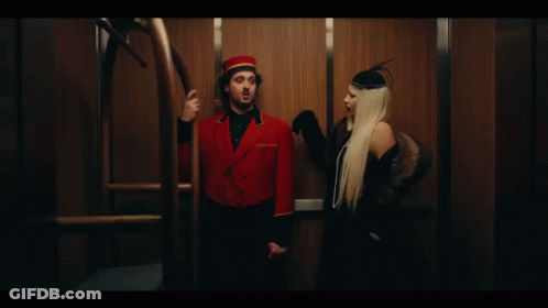 A Man And A Woman Are Standing Next To Each Other In An Elevator . GIF