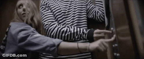 Man And Woman Standing In Elevator Woman In Striped Shirt GIF