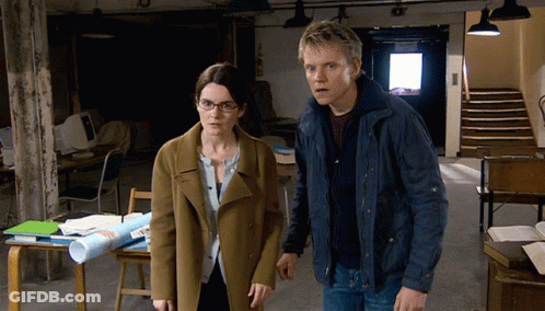 A Man And A Woman Are Standing Next To Each Other In An Office GIF