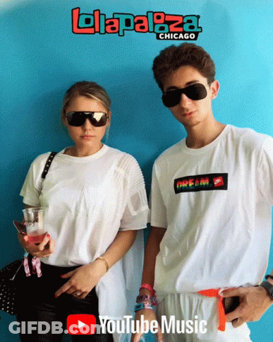 A Man And A Woman Are Standing Next To Each Other In Front Of A Blue Wall That Says Lolaplaza Chicago GIF