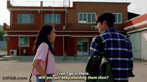 A Man And A Woman Are Standing Next To Each Other In Front Of A Building And Talking . GIF