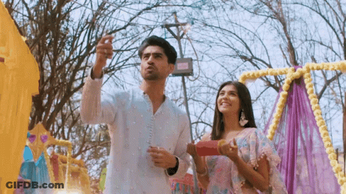 A Man And A Woman Are Standing Next To Each Other In Front Of A Colorful Display . GIF