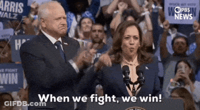 A Man And A Woman Are Standing Next To Each Other In Front Of A Crowd Of People . GIF