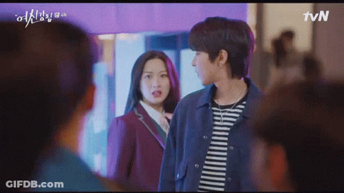 A Man And A Woman Are Standing Next To Each Other In Front Of A Crowd . GIF