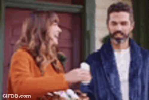 A Man And A Woman Are Standing Next To Each Other In Front Of A Door . GIF