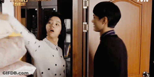 A Man And A Woman Are Standing Next To Each Other In Front Of A Door With The Year 1988 On It GIF