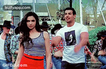 A Man And A Woman Are Standing Next To Each Other In Front Of A Group Of People . GIF