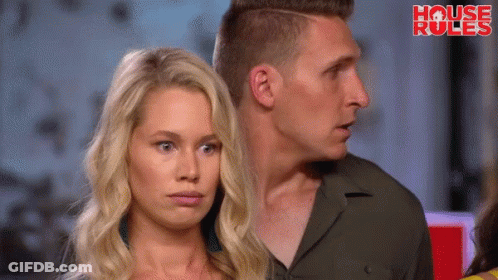 A Man And A Woman Are Standing Next To Each Other In Front Of A Sign That Says " House Rules " GIF