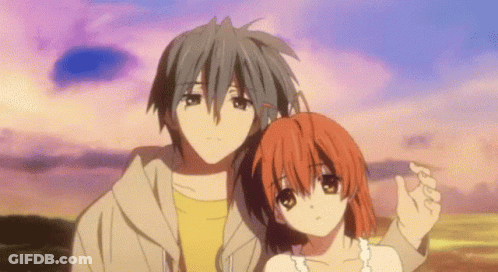A Man And A Woman Are Standing Next To Each Other In Front Of A Sunset . GIF