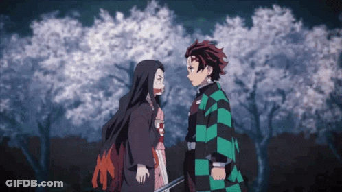 A Man And A Woman Are Standing Next To Each Other In Front Of A Tree . GIF