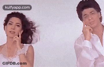 A Man And A Woman Are Standing Next To Each Other In Front Of A White Background . GIF