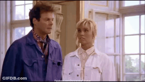 A Man And A Woman Are Standing Next To Each Other In Front Of A Window GIF