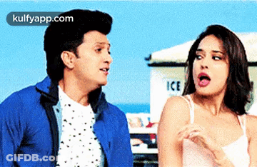 A Man And A Woman Are Standing Next To Each Other In Front Of An Ice Truck . GIF