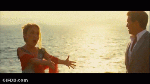 A Man And A Woman Are Standing Next To Each Other In Front Of The Ocean GIF