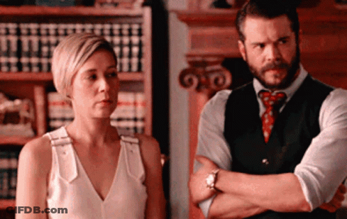 A Man And A Woman Are Standing Next To Each Other GIF