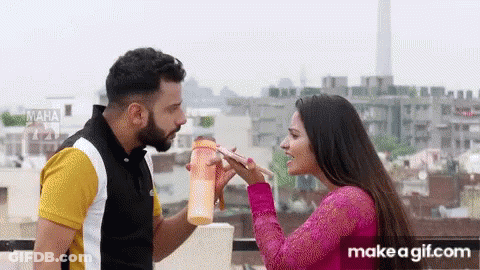 A Man And A Woman Are Standing Next To Each Other On A Balcony . GIF
