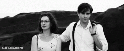 A Man And A Woman Are Standing Next To Each Other On A Hill . GIF