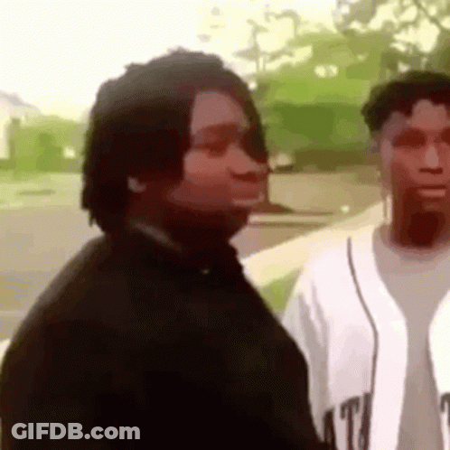 A Man And A Woman Are Standing Next To Each Other On A Sidewalk And Looking At Each Other . GIF