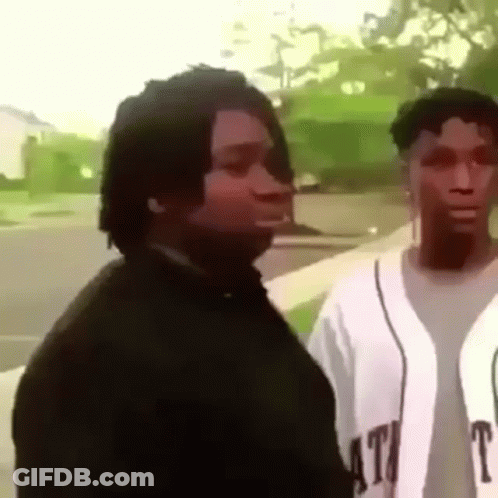 A Man And A Woman Are Standing Next To Each Other On A Sidewalk And Looking At Each Other . GIF