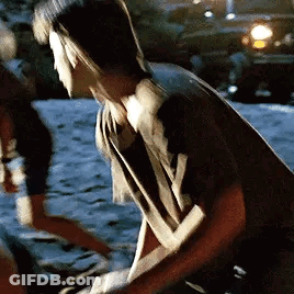 A Man And A Woman Are Standing Next To Each Other On A Sidewalk . GIF