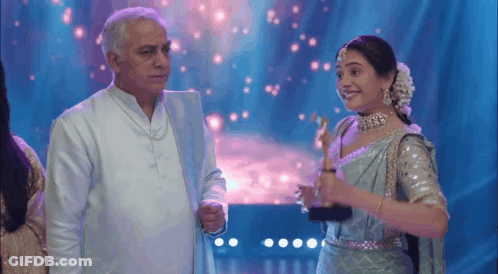 A Man And A Woman Are Standing Next To Each Other On A Stage . GIF