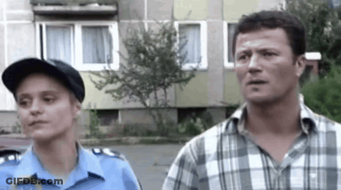 A Man And A Woman Are Standing Next To Each Other On A Street . GIF