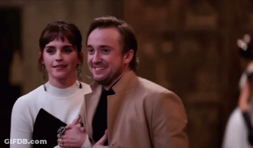 A Man And A Woman Are Standing Next To Each Other Smiling GIF
