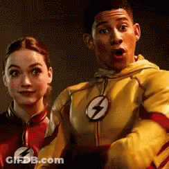 A Man And A Woman Are Standing Next To Each Other . The Man Is Wearing A Yellow Flash Suit . GIF