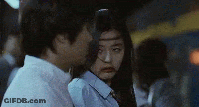 A Man And A Woman Are Standing Next To Each Other . The Woman Is Making A Funny Face . GIF